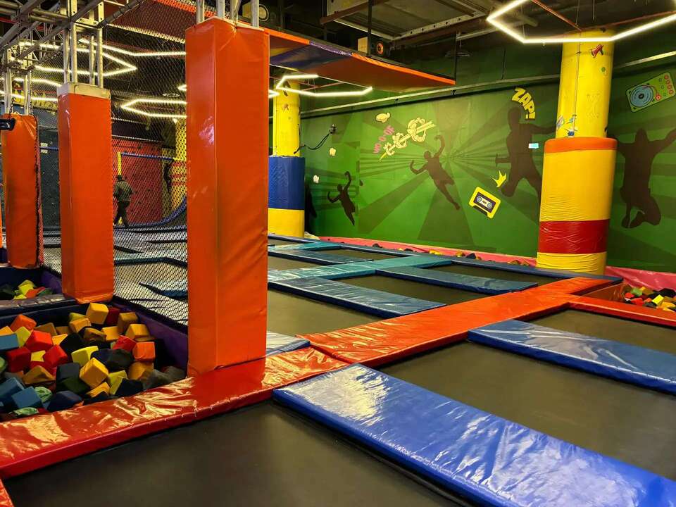 A vibrant indoor trampoline park filled with colorful balls and a spacious play area.