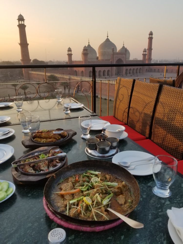 A table with food and plates on it overlooking the sunset, creating a picturesque dining experience.