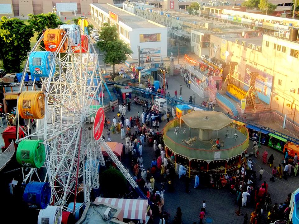 A vibrant carnival with a towering ferris wheel and a lively crowd of people enjoying the festivities.